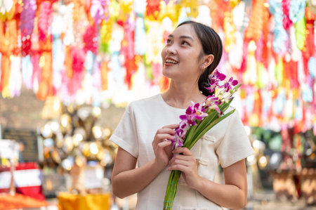 A charming Asian woman in a traditional Northern Thai dress admires the beautiful, colorful lanterns...