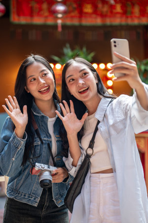 Two happy and beautiful Asian female friends enjoy traveling in Southeast Asia, taking a selfie...