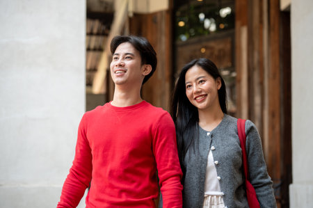 A lovely young Asian couple in cozy autumn clothes are enjoying a weekend shopping trip in the city,...