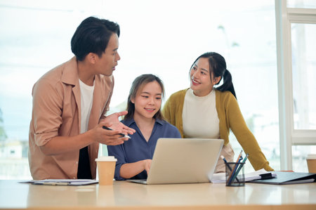 A team of smart young employees in casual clothes focused on discussing work, sharing helpful ideas, and planning upcoming projects together in a modern office. startup team, businesspeople, marketingの写真素材