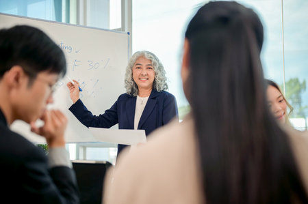 A professional Asian senior CEO speaks in the meeting with her marketing team in a modern meeting room, discussing and brainstorming the marketing strategies for the new project.の写真素材