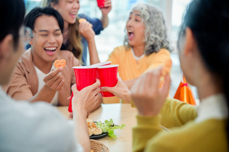 Smiling, cheerful diverse Asian employees enjoy drinks and conversations while celebrating their successful project at an office party. team building, celebration, office party, teamworkの写真素材