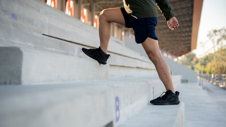 A cropped image of a man in sportswear running up the steps of a stadium, exercising in the morning. image with a copy spaceの写真素材