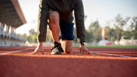 A cropped image of a strong man athletic runner in sportswear training in a stadium in the morning, preparing to run, get ready to run at the start point.の写真素材