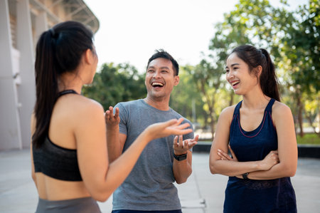 A group of sporty, happy Asian friends enjoy a conversation outdoors after training together. group of healthy people in sportswear standing and talking. wellbeing lifestyleの写真素材