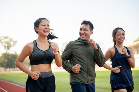 Portrait of a group of young, cheerful Asian athlete friends in sportswear running together in the stadium. friendship, people, sportの写真素材