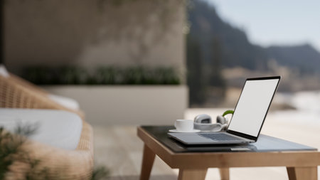 A close-up side view of a laptop with a white screen mockup placed on a coffee table in a contemporary and comfortable apartment balcony relaxation area. 3d render, 3d illustrationの写真素材