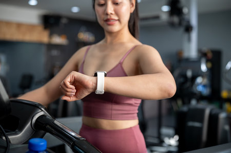 A cropped image of a sporty Asian woman in sportswear is checking her calorie count on her...