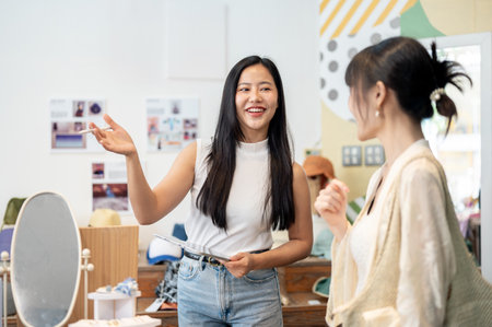 A friendly and service-minded Asian female clothing store employee or owner is talking to a...