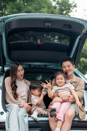 A happy and cheerful Asian family sitting in the trunk of their car, smiling at the camera and enjoying their road trip or camping adventure together. family car, happy moment, travelingの写真素材