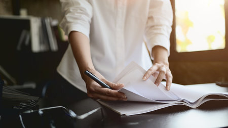 A close-up of a professional female architect or engineer is reviewing documents at her desk in the office.の写真素材