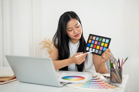 An asian woman is showing and explaining a color palette to her client or coworker in online meeting, Interior Designer or Graphic Designer in office.の写真素材