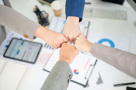 Top view of businessman and woman or office workers bumping fists over table with scattered...