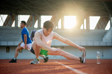 Two asian athlete men are stretching their muscles together on the racetrack. Jogging or Running, Outdoor exercise or work out, Sport and health.の写真素材