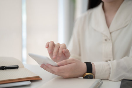 Close up of female office worker hand holding and using a calculator while sitting at working table in office. Desk Job, Corporate Job, Modern Company.の写真素材