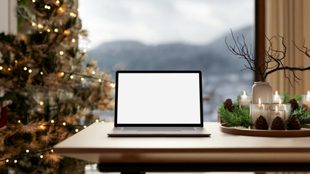 White screen laptop with decoration items on tray over wooden table aside a lighting Christmas tree. Advertising Mockup, 3D Rendering 3D Illustration.の写真素材