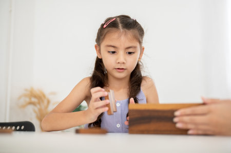 Asian kid or a little girl in purple shirt is keeping wooden blocks in a box with her parent after done playing. Kids toys, Wooden blocks.の写真素材
