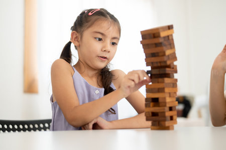 Asian kid or a little girl in purple shirt is surprised with a tilting wooden blocks tower during a wooden block pull out. Kids toys, Wooden blocks.の写真素材