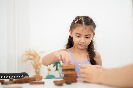 Asian kid or a girl in purple shirt playing or building a wooden blocks tower with her parent on table in white room. Kids toys, Wooden blocks.の写真素材