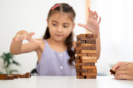 An asian kid or a girl in purple shirt playing or building a wooden blocks tower with her parent on table in white room. Kids toys, Wooden blocks.の写真素材