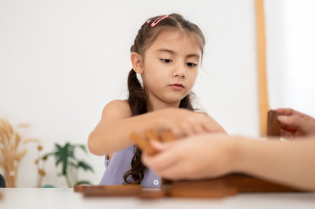 Asian kid or a little girl in purple shirt sitting and playing a tower building game with parent in the white room. Wooden blocks, Kids toys.の写真素材