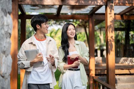 Smiling asian friends or a couple of man and woman walking together in the wooden corridor. Working or Study outdoor, Garden Cafe or Restaurant.の写真素材