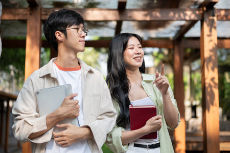 Asian friends or a couple of man and woman are walking and looking around in wooden corridor. Working or Study outdoor, Garden Cafe or Restaurant.の写真素材
