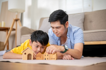 Close up of asian father and his elementary school son playing with wooden house toy on carpet in their living room. Kid block toys, Fun activity.の写真素材
