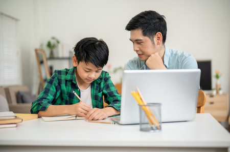 Father explaining to his son while looking at his workbook during homework teaching. Elementary Schoolboy, Kids education, Family bonding.の写真素材
