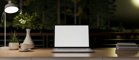 Blank screen laptop and coffee or tea cup with books on wooden table under lamp light at night. Study or Working corner, 3d Rendering, 3d Illustration.の写真素材
