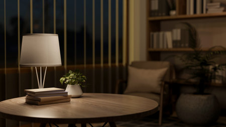 Books and potted plant on wooden round table under lamp light in a living room or a library. Working...