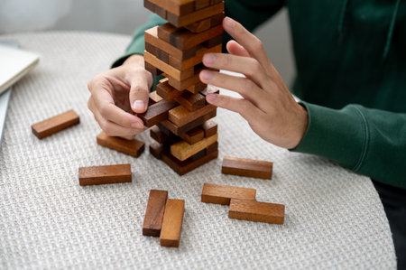 Close up of man's hand pulling out a pieces of wooden block in tower building game as playing alone. Party game, Learning activity.の写真素材