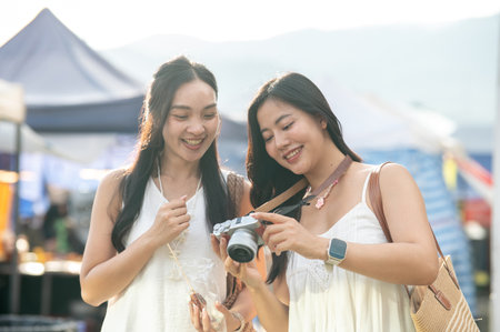 Two pretty asian women best friends standing and looking at camera going on a trip in local market. Travel Trip, Tourist destination, Holiday Vacation.の写真素材