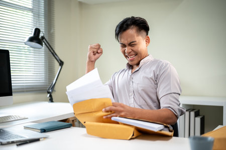 Asian businessman office worker looking at documents and raising a fist in excited at white table.