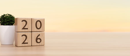 2026 new year countdown wooden blocks calendar aside potted plant on counter table in warm light....