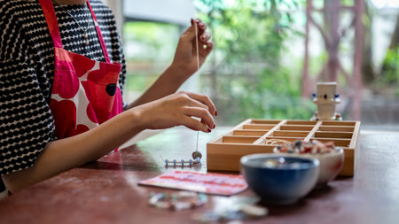 Painted nails woman pottery artist threading ceramic beads making a colorful bracelet in a class or studio. Jewelry, Handmade Product, Art Workshop.の写真素材