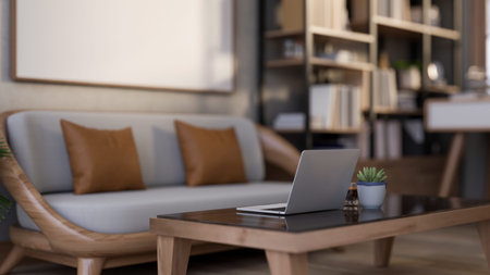 Wooden sofa with pillow cushions and laptop aside coffee and potted plant on glass top wooden table....