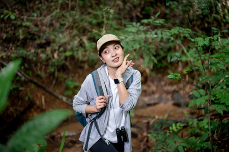 Pretty asian woman tourist walking holding bag strap and wiping sweat during forest hiking or...