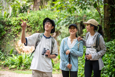 Tourist man and woman friends group with binoculars looking around while hiking or trekking in the...