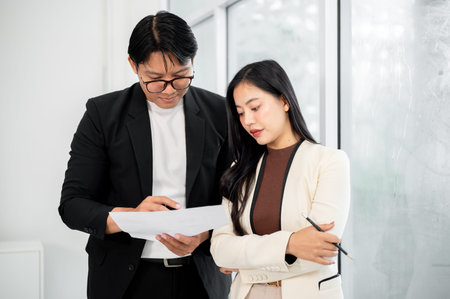 Serious businessman and woman or office worker standing looking intently at the important document.