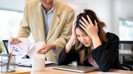 Asian businesswoman holding head in pain or getting stressed after making a mistake at office's table. Meeting room, Corporate jobs, Modern company.の写真素材