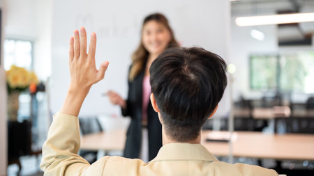 Close up man raising hand asking question to woman speaker after explaining plan on board in office. Meeting room, Corporate jobs, Modern company.の写真素材