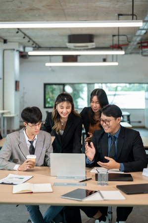 Smiling businesswoman looking at laptop talk or explain to coworker at wooden table in meeting room....