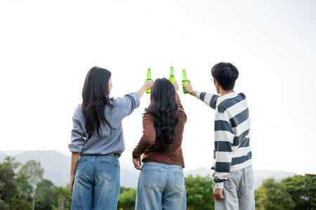 Friends woman and man holding raising drink bottle while standing in mountain view grass field....