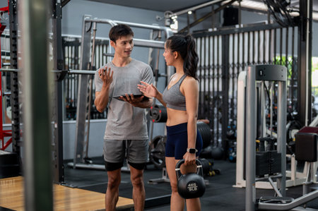 Fitness trainer coach man holding clipboard talking about exercise class to woman client in the gym....