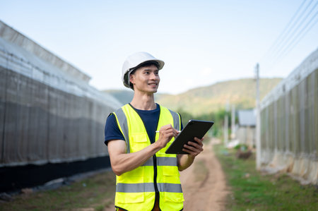 Asian engineer man wearing safety vest and hard hat helmet write in tablet standing aside...