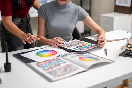Close up of woman holding pencil explaining color to friend coworker at table in home office studio....