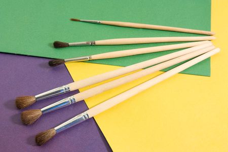 various brushes on background of a different coloured paper 