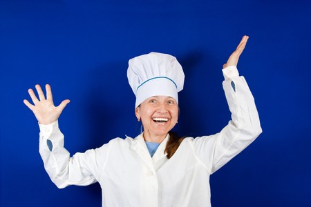 Senior cook woman in toque  over blue backgroundの写真素材