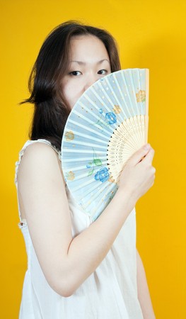 attractive asian girl with fan  over  yellowの写真素材
